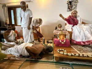 4. After the recitation the Vedic scholar prostrates to Amma who is blessing him by sprinkling akshata or yellow rice on him.